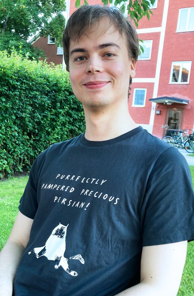Young man wearing black Uniqlo UT “Purrfectly Pampered Precious Persian!” T-shirt featuring Marie Åhfeldt’s cat illustration.